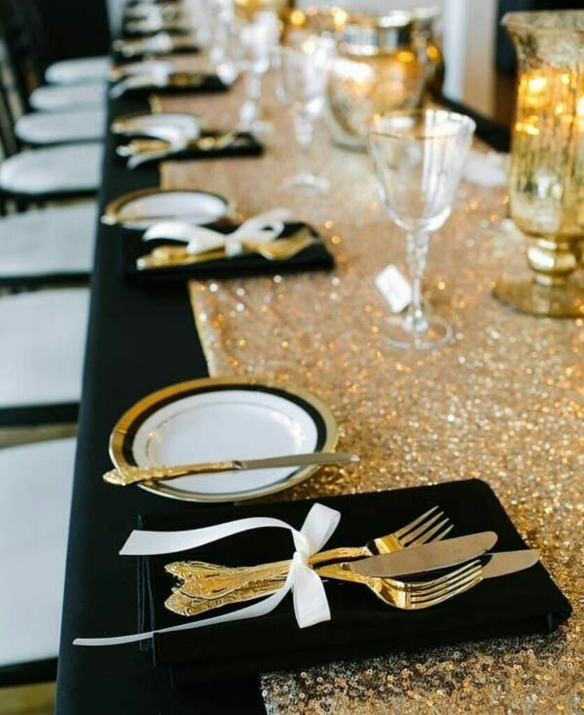 Glitter runner with black linens, gold cutlery tied in white ribbon.
