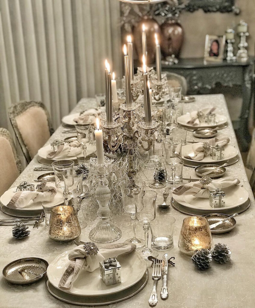 Silver candelabra, mercury glass and pinecones on neutral elegant table.