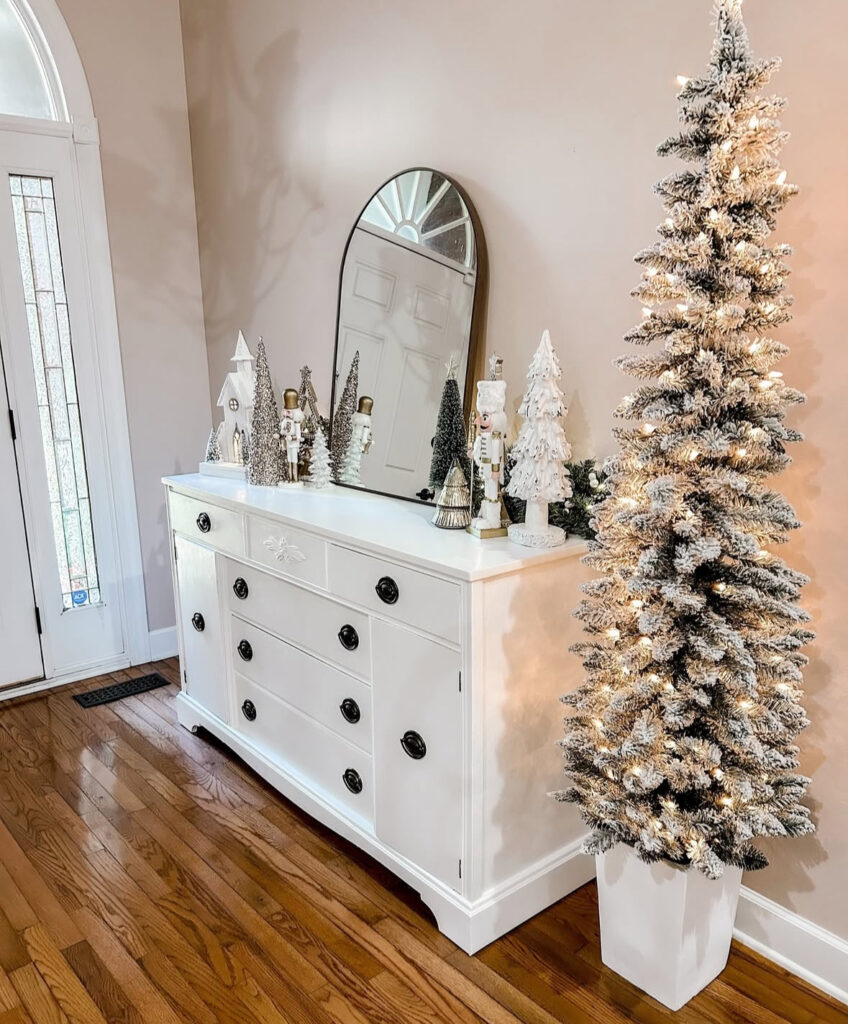 Slim snowy Christmas tree styled beside a white console table