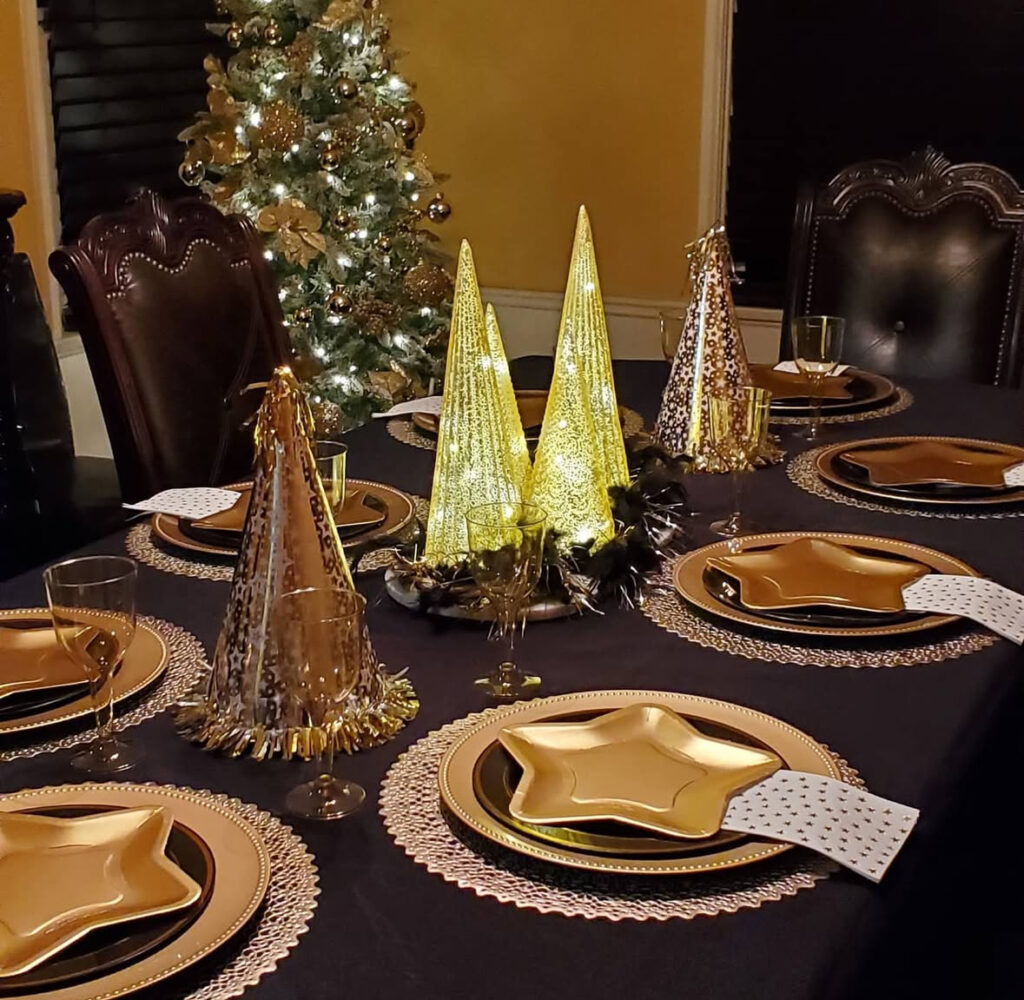 Black cloth with gold star-shaped plates and illuminated cone trees.