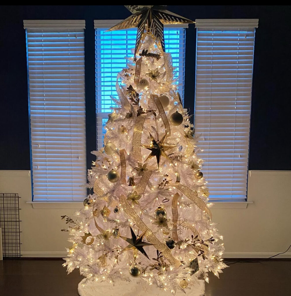 Starry night white and gold christmas tree with metallic ribbon and dramatic topper.