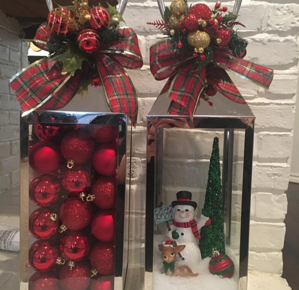 Two lanterns topped with tartan ribbon and holiday greenery