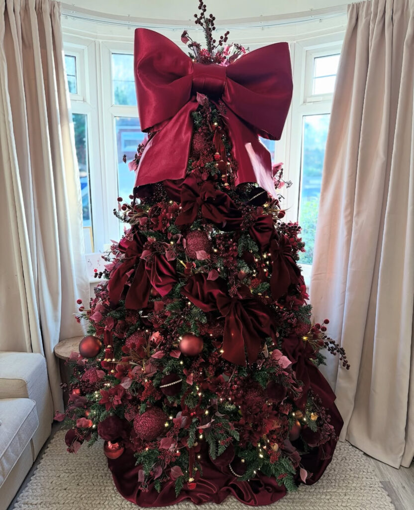 Tall burgundy Christmas tree with an oversized giant bow
