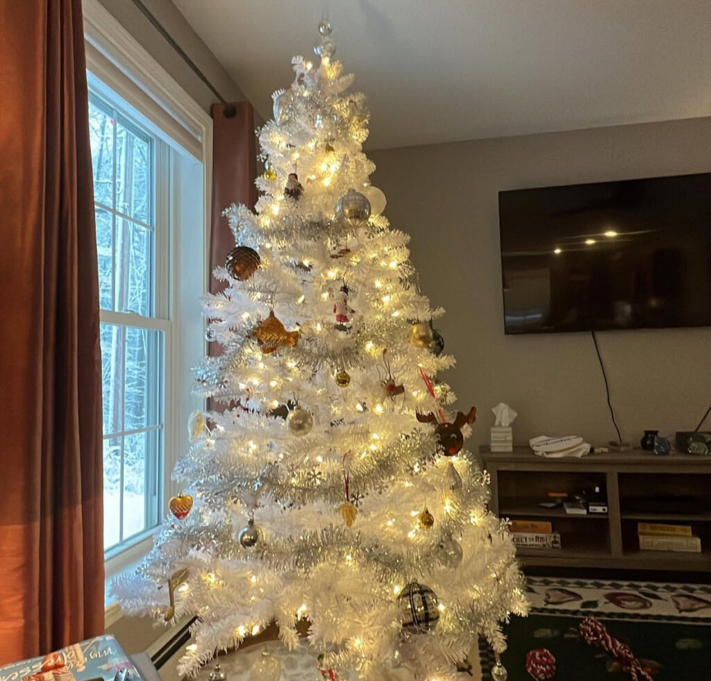Window-lit snowdrift with mixed white christmas tree ornaments and warm twinkle lights.