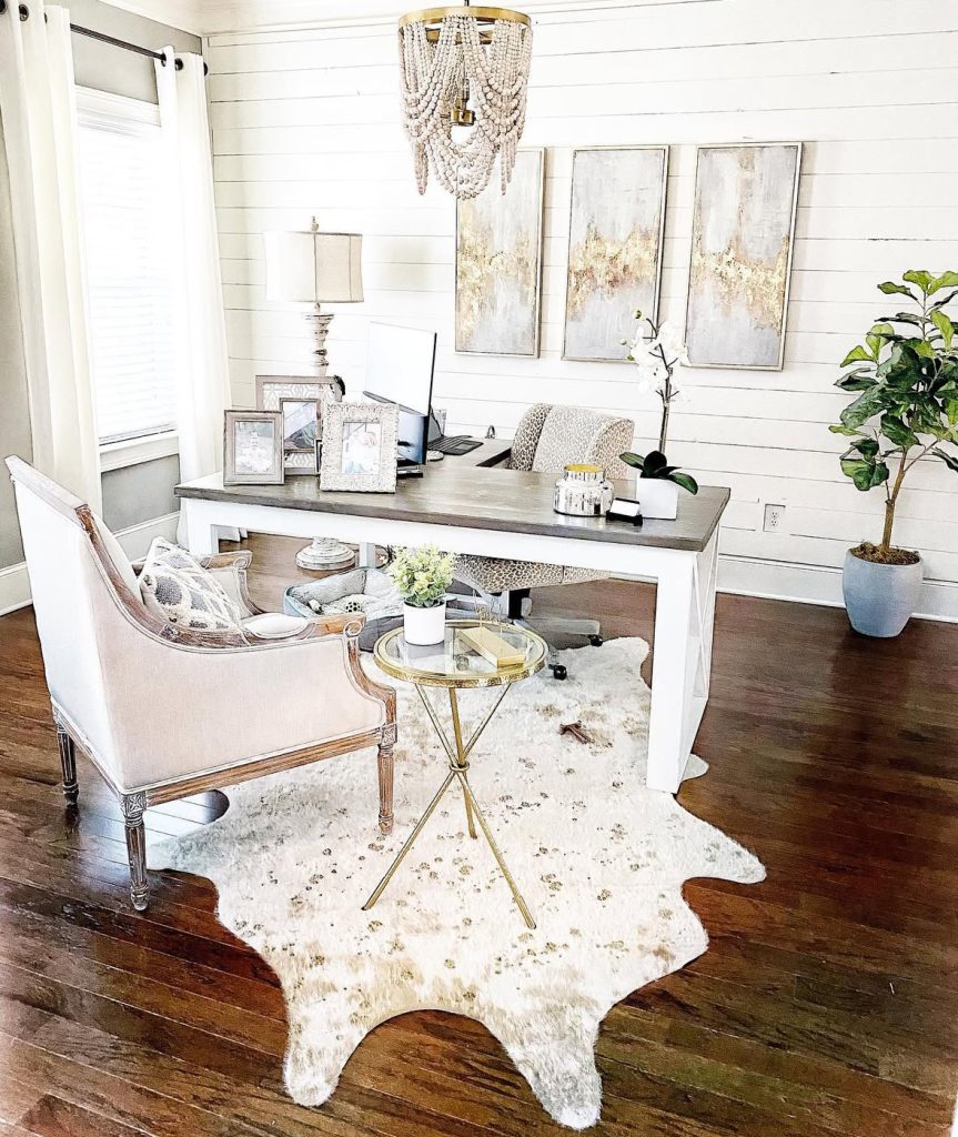 Rustic farmhouse office with white shiplap walls and a chandelier