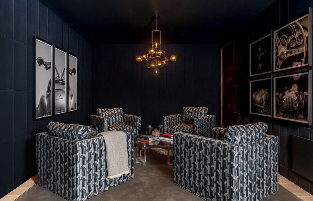 Graphic armchairs and oversized car photography on dark walls highlight sleek man cave wall ideas for auto lovers.