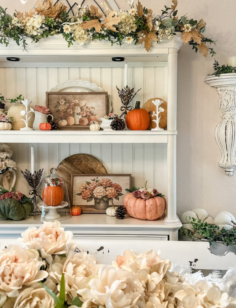 White hutch styled with pumpkins, florals, and vintage art for autumn shabby chic home decor ideas.