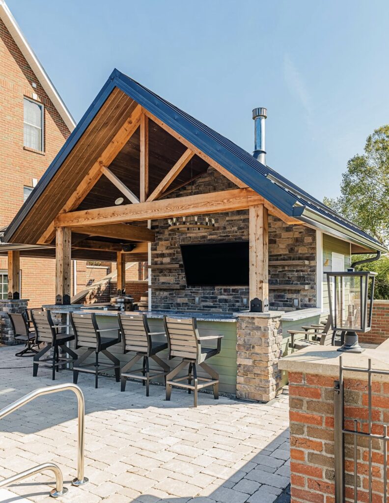 Poolside bar pavilion with TV and bar seating as inspiration for backyard covered outdoor kitchen ideas