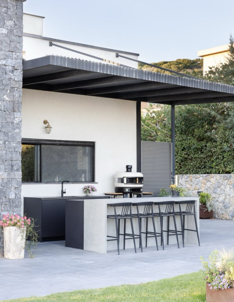 Flat-roofed modern home with concrete bar island, sink, and pizza oven offering minimalist backyard outdoor kitchen ideas