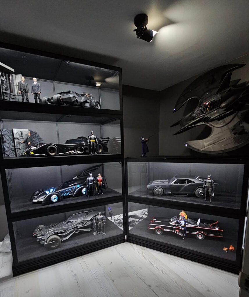 Illuminated display cases filled with Batmobiles and figures turn this room into themed black man cave ideas for comic collectors.