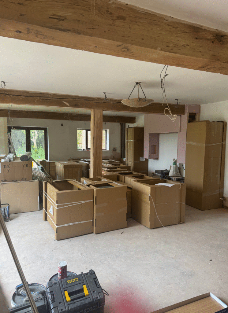 Kitchen space mid-renovation with boxes, beams, and new cabinets ready to fit, capturing real-life barn conversion ideas in progress.
