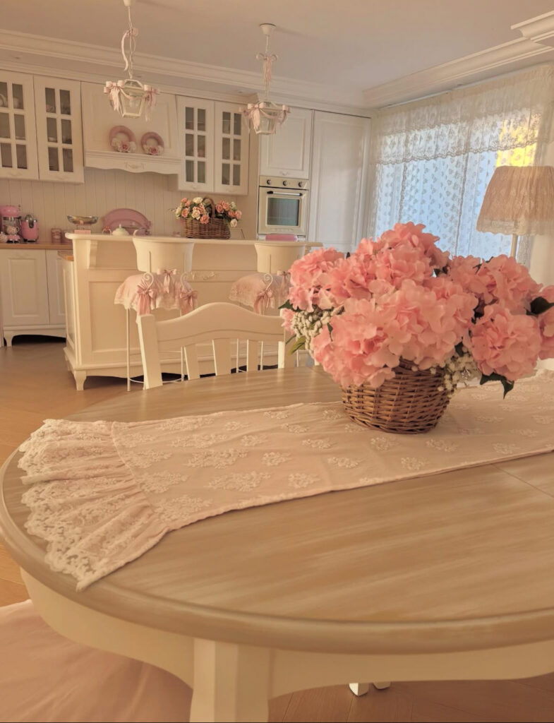 Cream and blush kitchen with lace curtains and pink accents showing romantic shabby chic decor ideas.