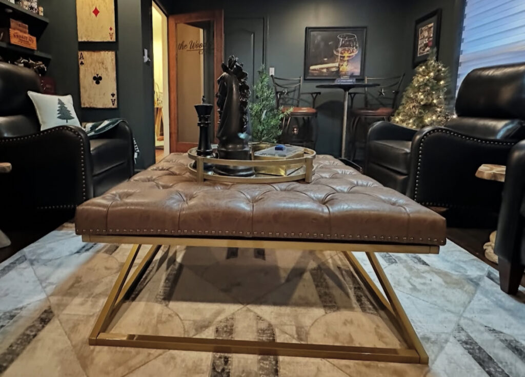 A tufted ottoman, leather recliners, and game-themed art illustrate low budget small man cave ideas perfect for poker nights.