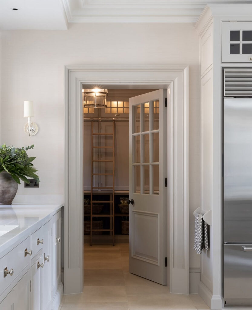 from the main kitchen a glazed door opens to a walk in pantry with high shelves and a rolling ladder