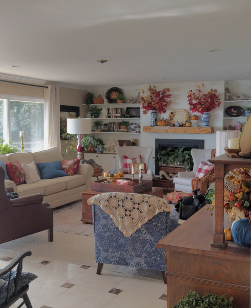 Cozy sofas, colorful pillows, and packed shelves create a rustic french country living room that feels collected and family friendly.