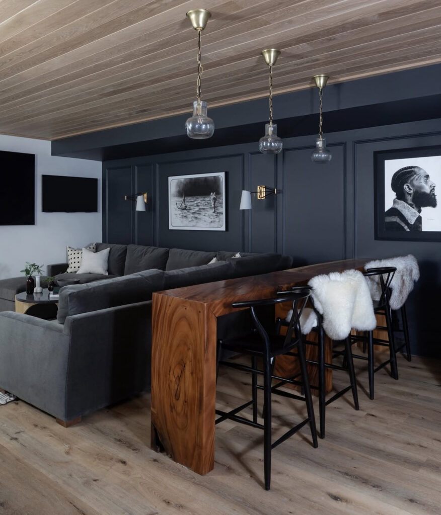 A slim live-edge bar behind the sofa and dark paneled walls demonstrate low budget small man cave ideas that still feel upscale.