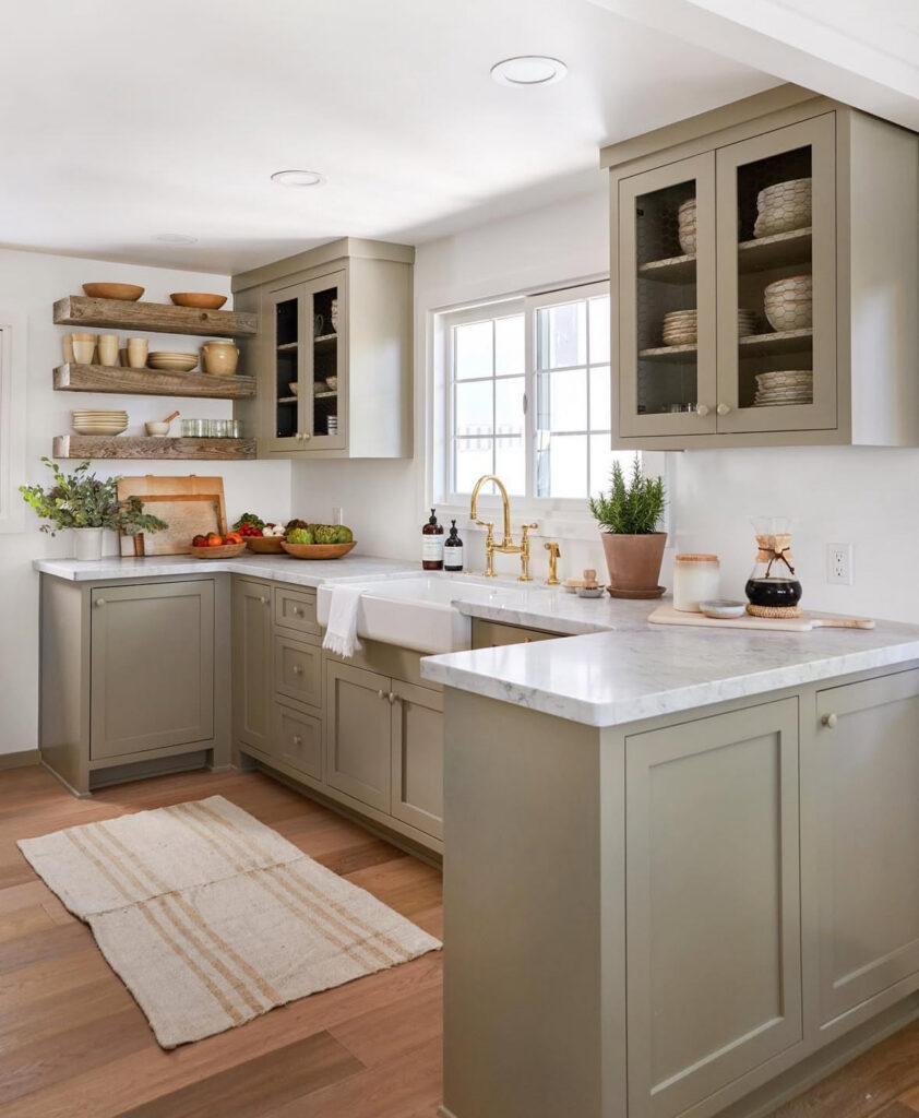 cozy sage green lake house kitchen with farmhouse sink brass faucet marble counters