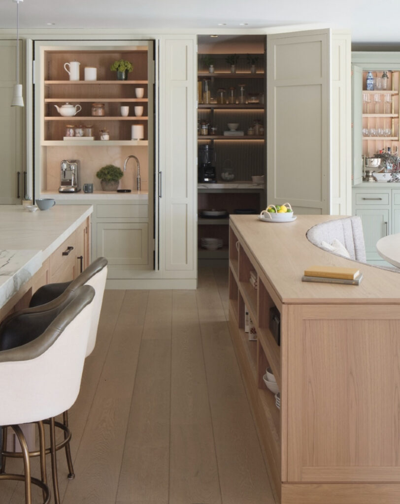 neutral kitchen with tall folding doors hides a double depth prep room full of walk in pantry ideas like lit shelves and extra counter space