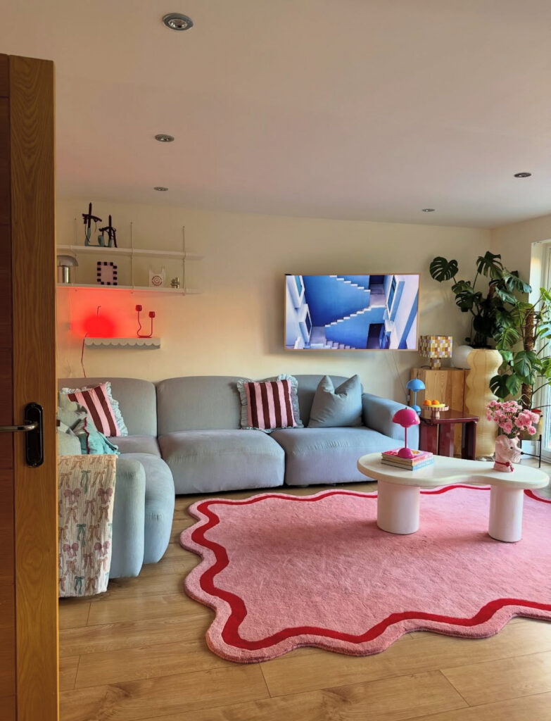Pastel living room with curvy pink rug, blue sofa, and sculptural lamps, sparking bright and playful eclectic home decor ideas.