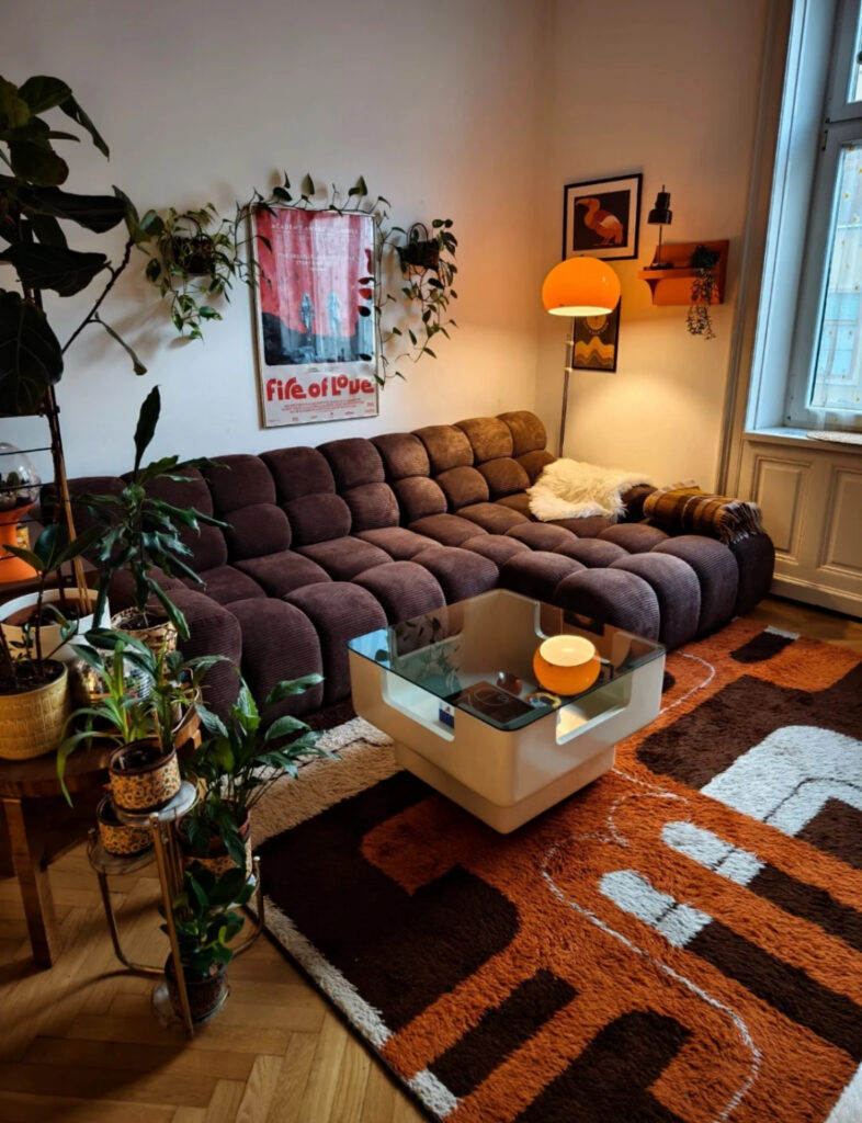 Retro-inspired lounge with a tufted brown sofa, orange lamp, and geometric rug that perfectly capture an expressive eclectic home decor style.