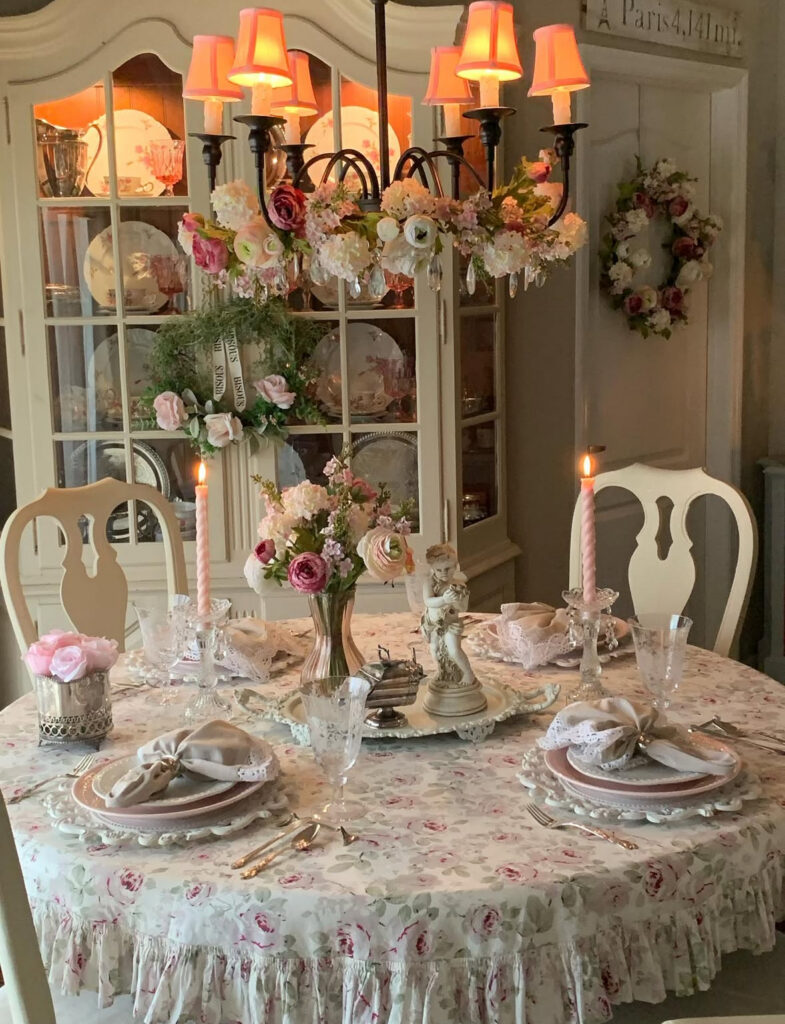 Round dining table with floral cloth, candles, and china cabinet for elegant shabby chic home decor ideas.