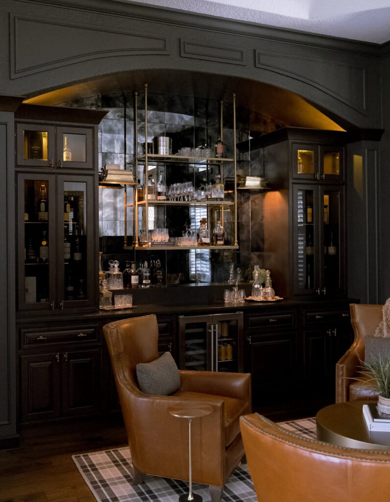 A mirrored back bar, glass-front cabinets, and caramel leather chairs present refined man cave ideas inspired by classic clubs.