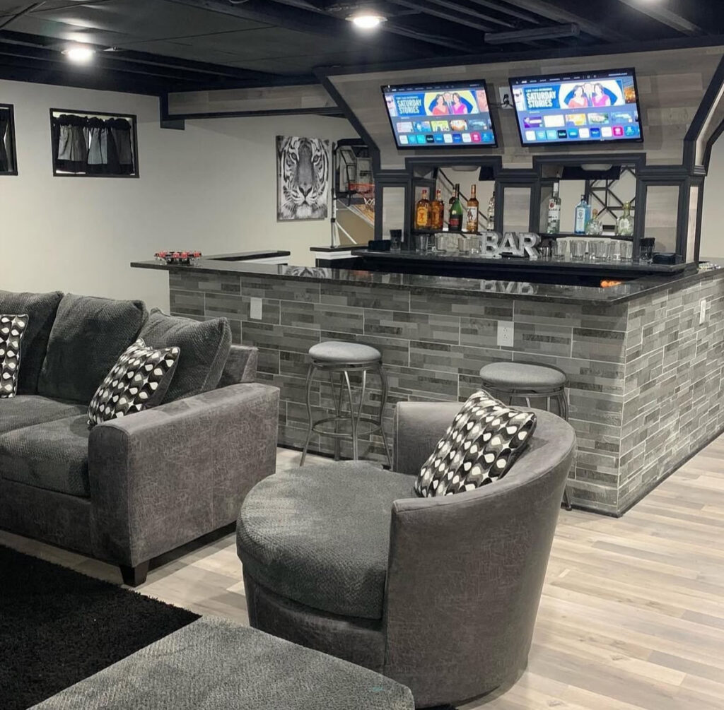 A compact bar, sectional seating, and tiled front counter deliver practical basement man cave ideas for entertaining friends.