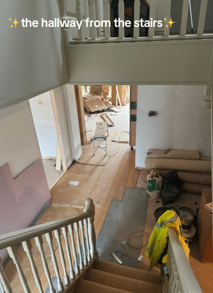View down the stairs into a messy hallway with new flooring going in, highlighting real-life barn conversion ideas for updating circulation spaces.
