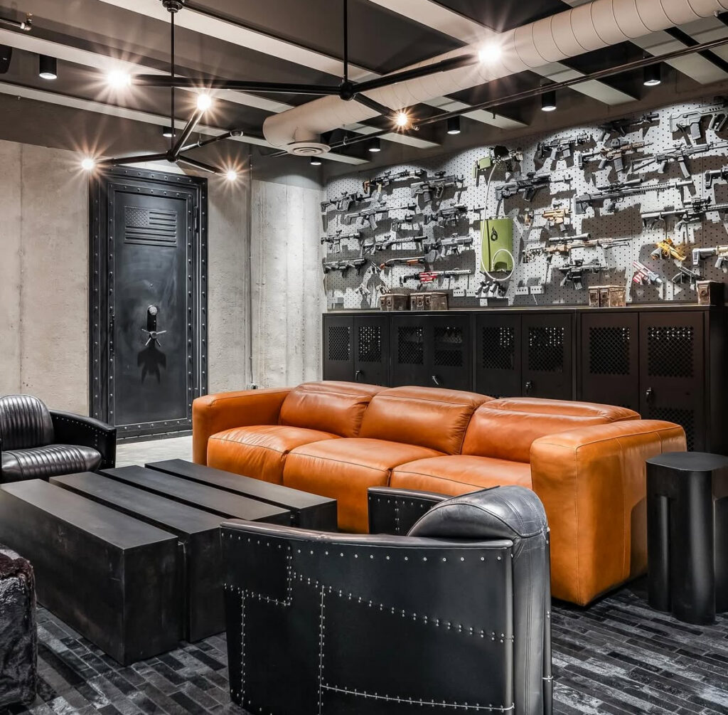 Concrete walls, a caramel sofa, and an industrial display wall create high-impact man cave ideas with a bunker vibe.