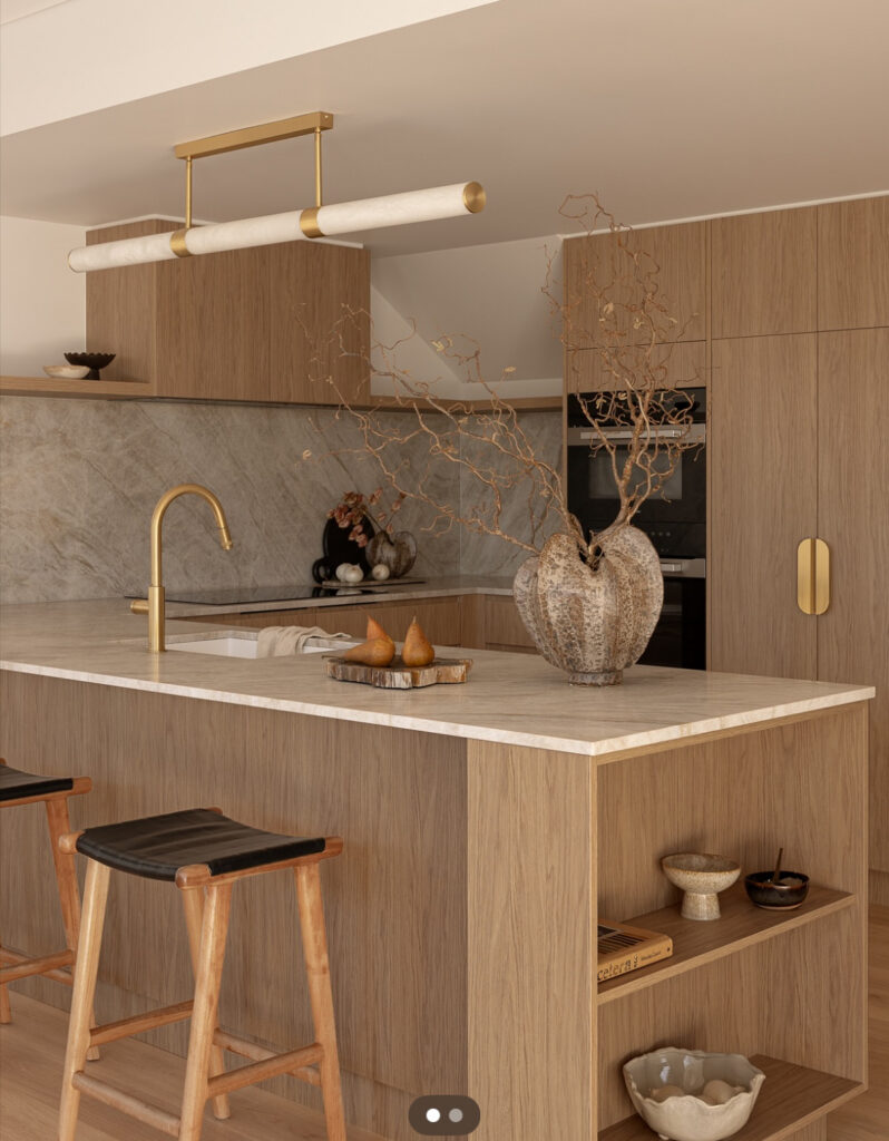 Japandi kitchen with oak cabinets, brass hardware, and marble accents.