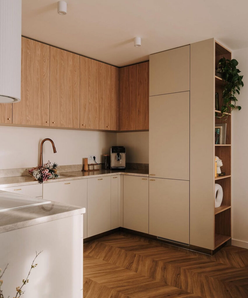 Japandi kitchen featuring a chevron wood floor and beige minimalist cabinets.
