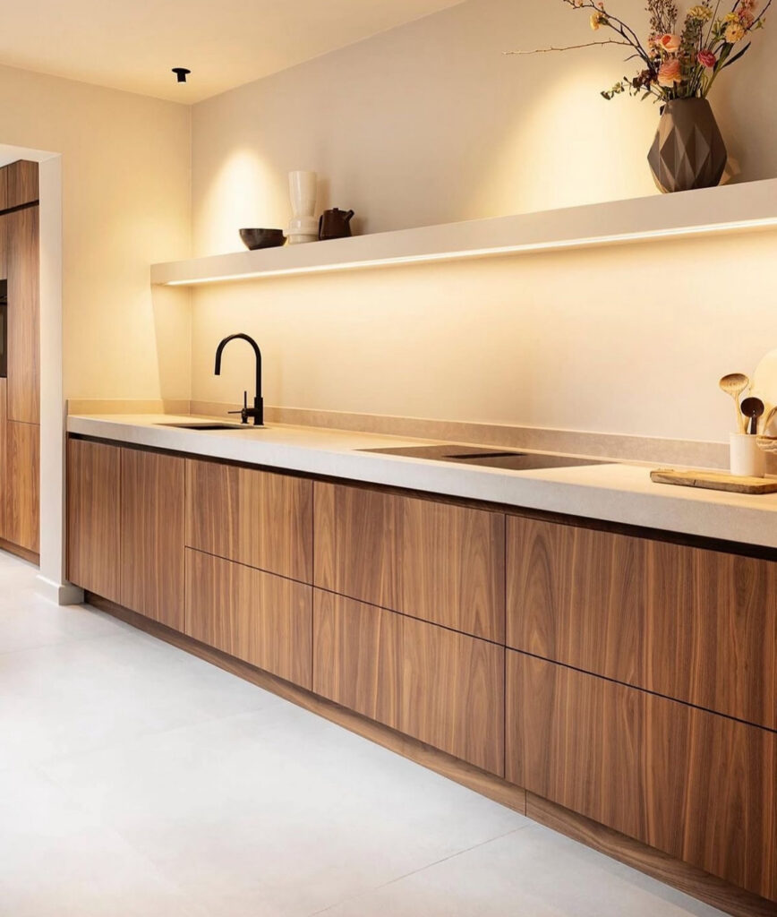 Long open shelf with integrated lighting in a minimalist Japandi kitchen.