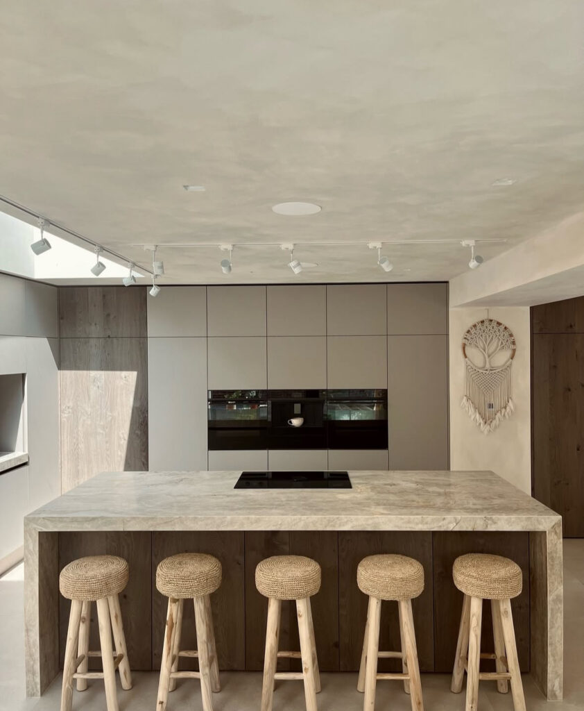 Stone-clad Japandi kitchen island paired with minimalist stools.