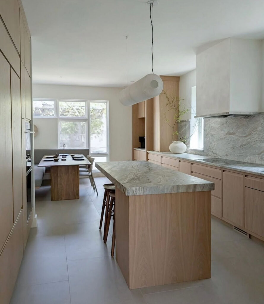 Japandi kitchen featuring a stone slab island beside a built-in banquette.