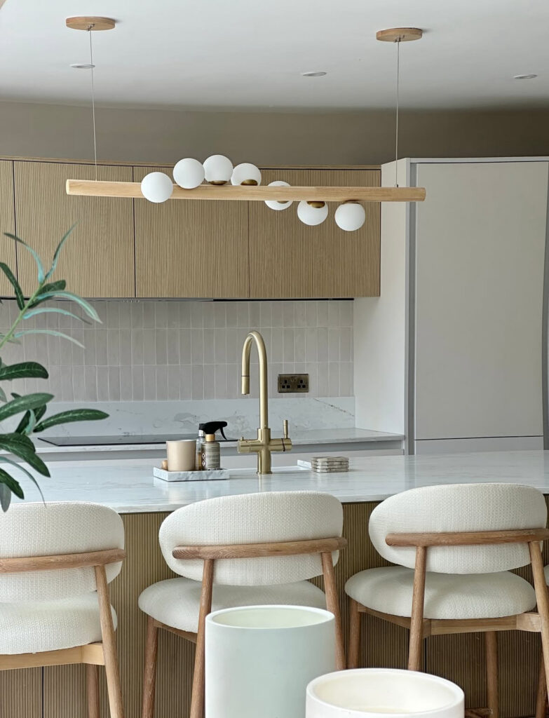 Japandi kitchen with a fluted island and cream boucle counter stools.
