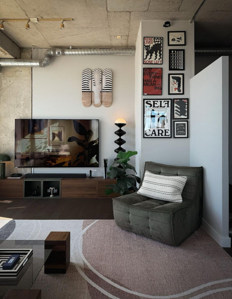 Industrial loft with gallery prints, wood console, and leafy plant giving fresh living room wall ideas with tv that still feel creative and collected.