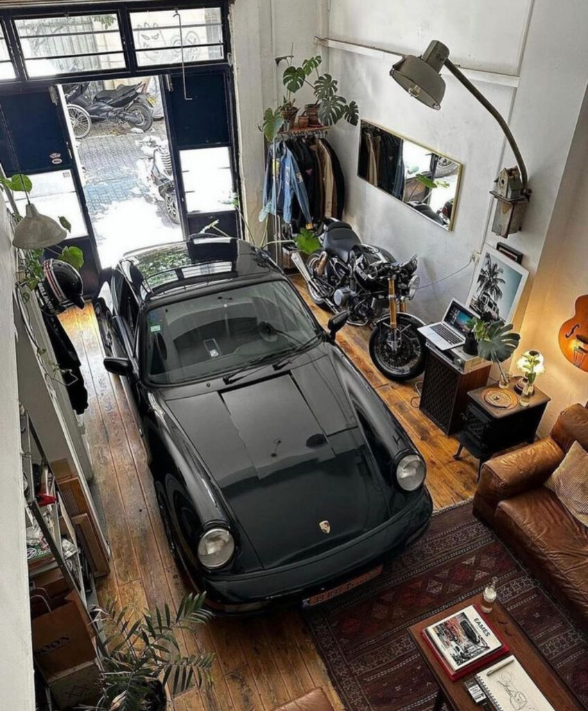 A vintage Porsche parked beside a leather sofa and motorcycle embodies edgy garage man cave ideas in an urban loft.