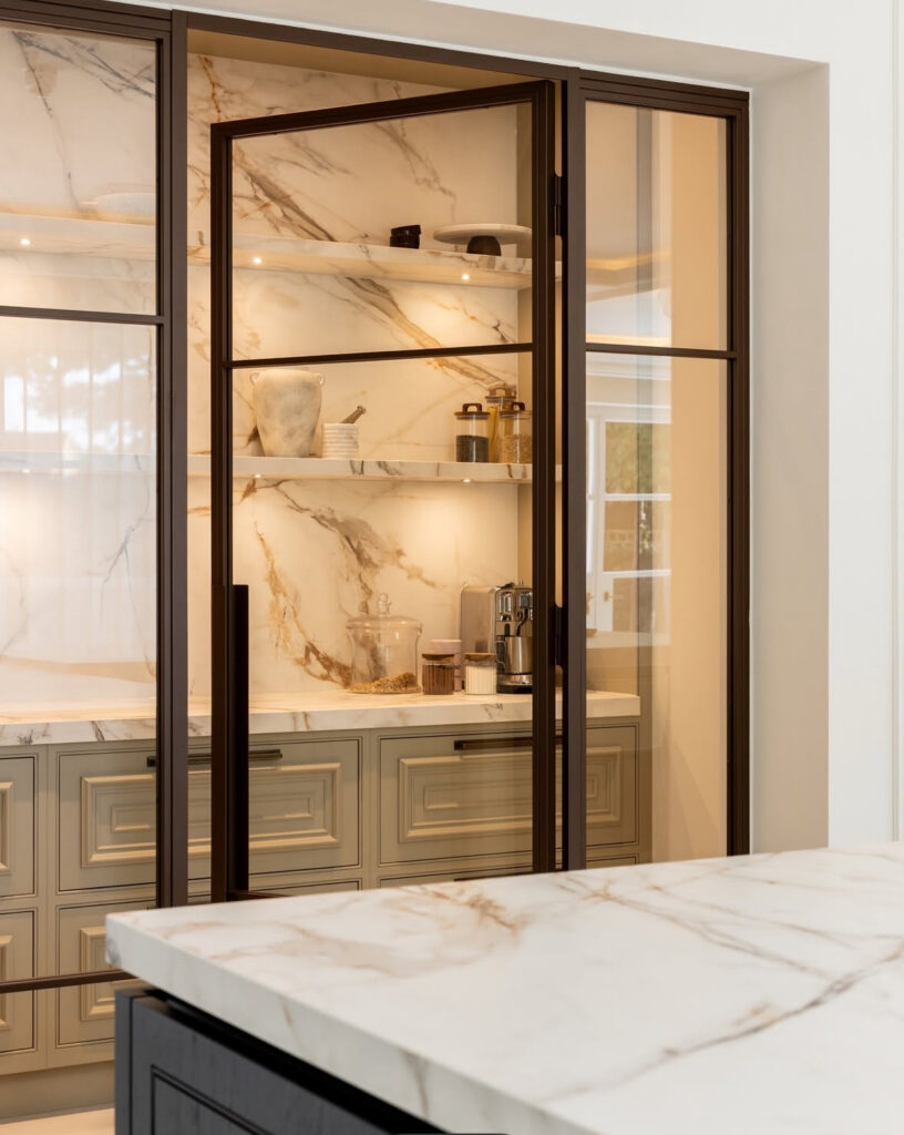 marble clad walls and counters behind metal framed glass doors highlight high end walk in pantry ideas for a showpiece kitchen