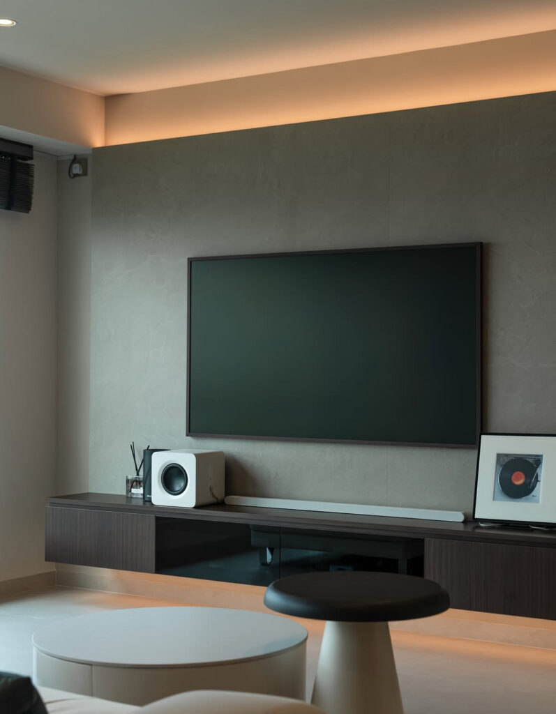 Minimal floating console, large flat screen, and soft LED strip lighting offering modern living room tv wall ideas in a neutral apartment.