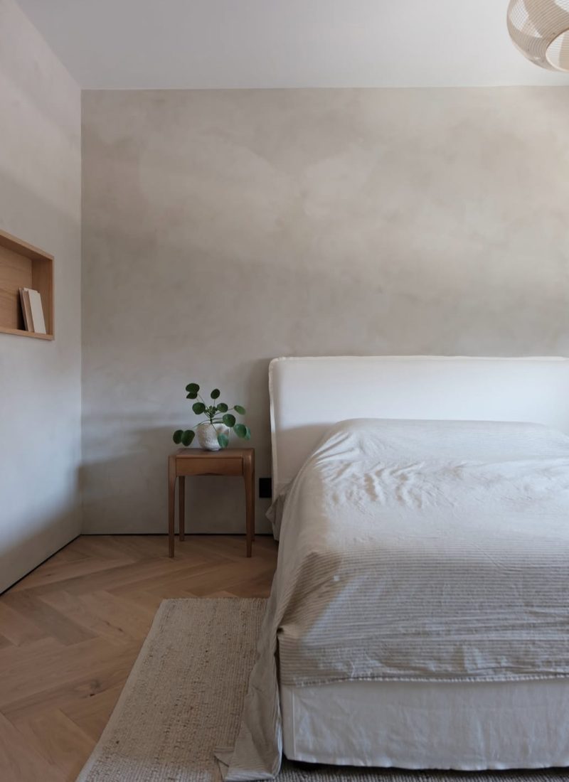 Minimalist Japandi bedroom with limewashed walls, herringbone oak floor, and a low white bed