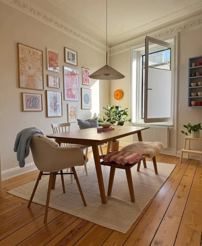 Airy dining room with wood table, modern chairs, and soft pink art prints, embodying minimal yet warm modern eclectic home decor.