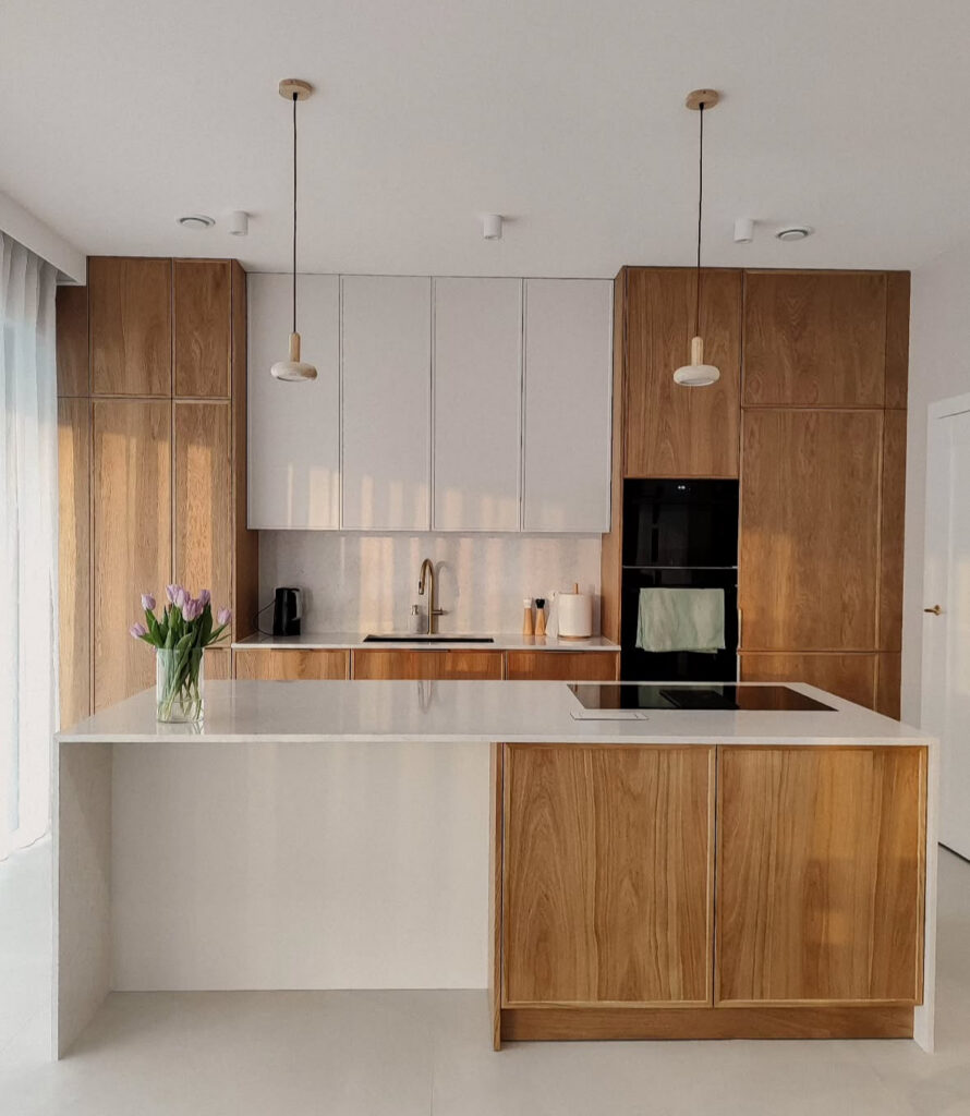 Modern Japandi kitchen peninsula topped with a vase of white tulips.