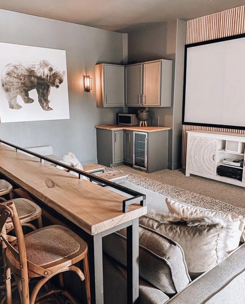 Soft neutrals, a slim bar behind the sofa, and a large screen show relaxed small man cave ideas for a minimalist theater.
