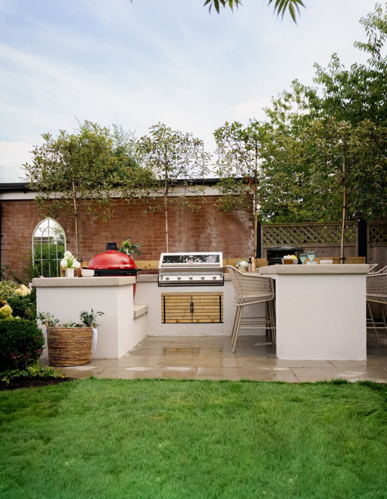 Open-air grill station with red ceramic cooker and bar seating along the lawn inspiring garden-focused outdoor kitchen ideas