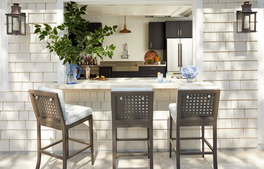 Indoor kitchen opening to a bar counter with stools through a wide window serving fresh outdoor kitchen ideas