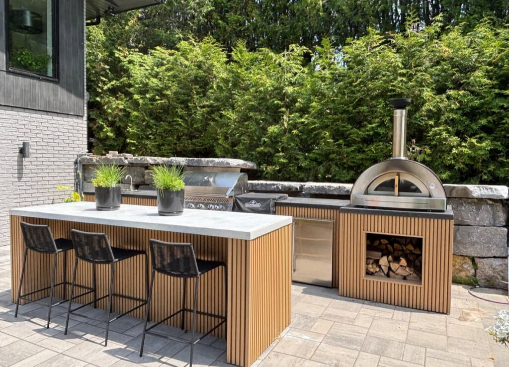 Patterned tile island under a sleek metal pergola with red oven highlighting backyard covered outdoor kitchen ideas