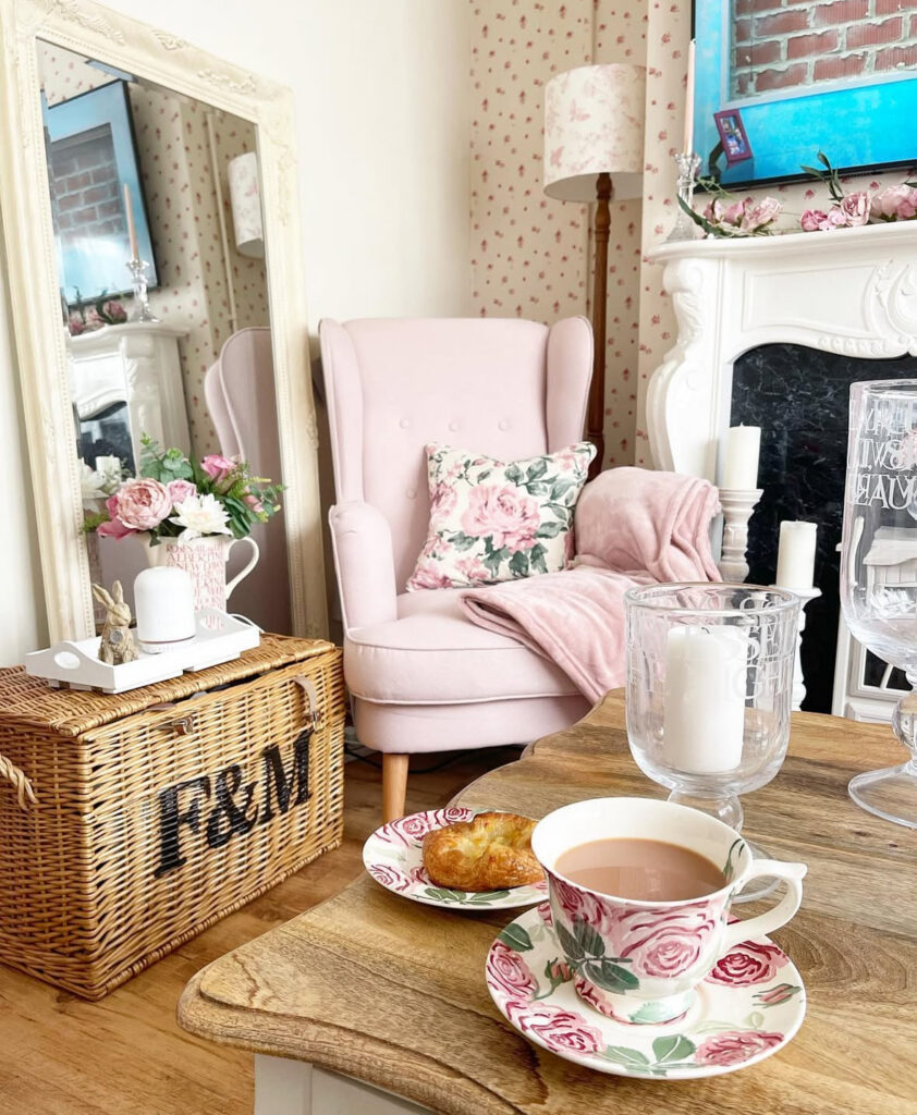 Pink armchair by a rustic coffee table with floral china offering soft shabby chic decor ideas.