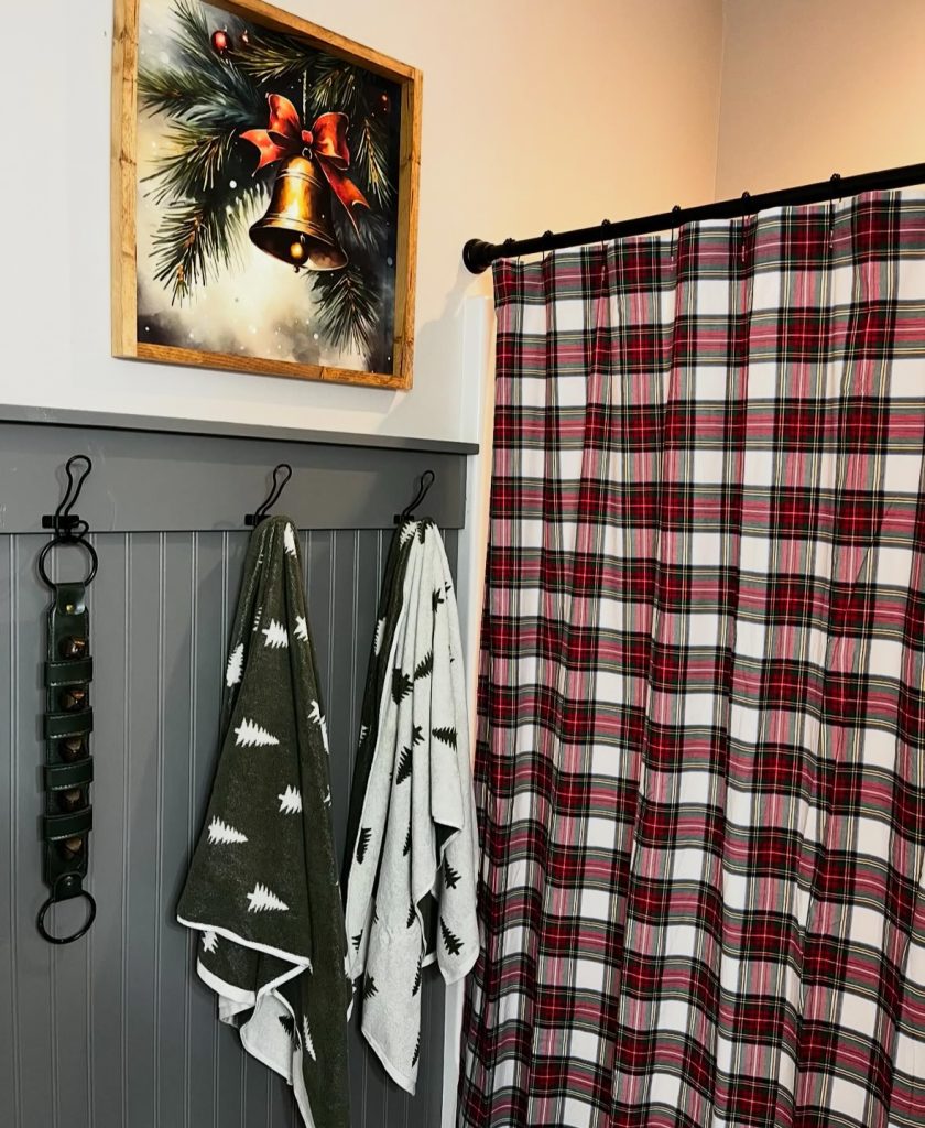 Bathroom with plaid Christmas towels and bell-themed wall art