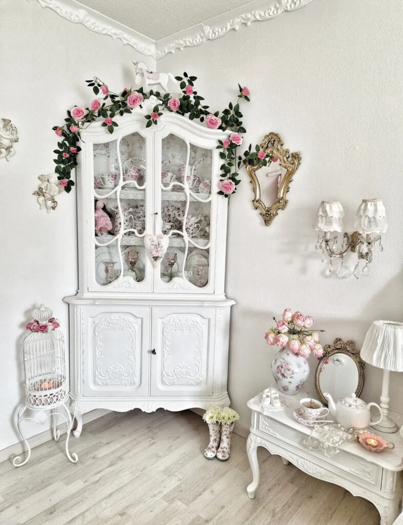 Corner cabinet with pink roses, floral china, and white birdcage styled as shabby chic bird cage decor.