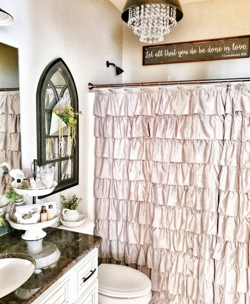 Bathroom with ruffled shower curtain, crystal light, and rustic sign used as shabby chic wall decor.